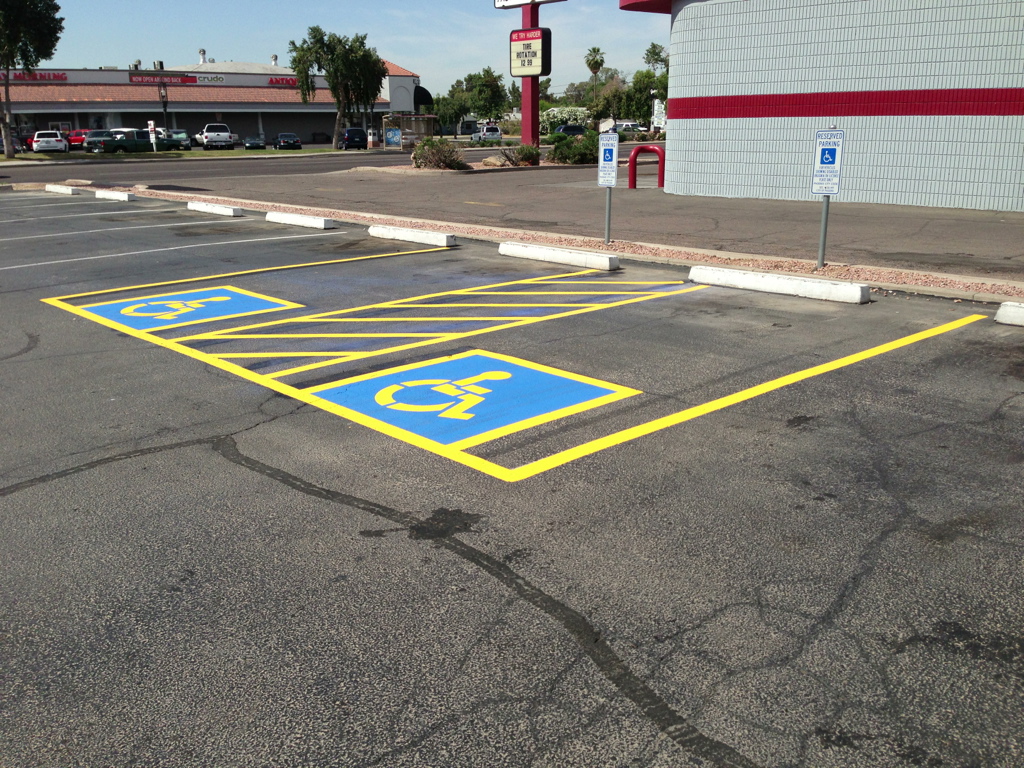 We Do Lines Arizona - The parking lot, featuring professional line striping, has three available handicapped parking spaces marked in blue and yellow, conveniently located near a retail area.